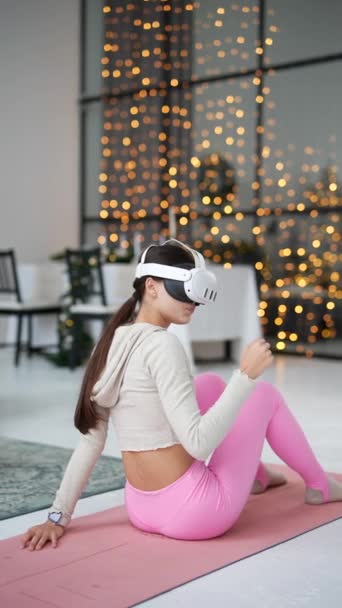 Een mooie jonge vrouw in een virtual reality headset doet beenoefeningen tijdens een thuistraining. Hoge kwaliteit 4k beeldmateriaal - Video