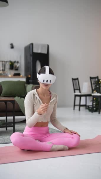 Практикуя йогу дома в праздничный период, стройная юная леди пользуется гарнитурой виртуальной реальности. Высококачественные 4k кадры - Кадры, видео