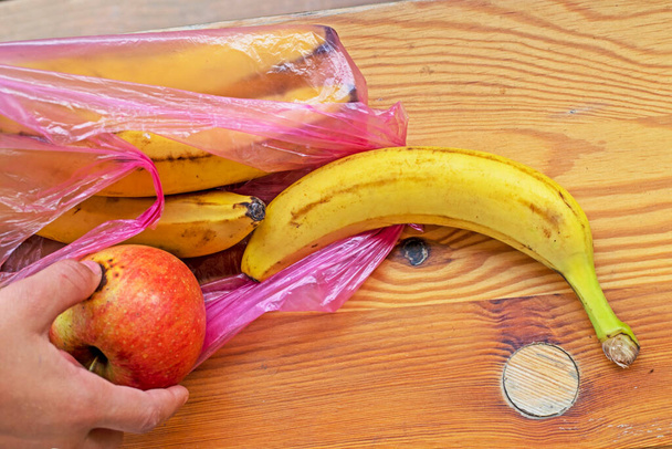 kivenni a banánt egy eldobható műanyag zsákból egy fa felületre. környezetvédelmi ökológusok - Fotó, kép