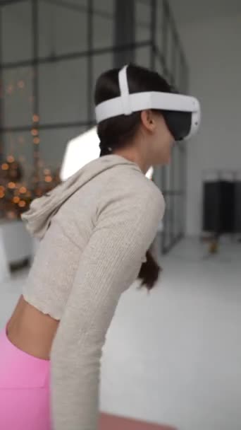 Sportowa młoda kobieta używa zestawu słuchawkowego do ćwiczeń wirtualnej rzeczywistości podczas Świąt Bożego Narodzenia. Wysokiej jakości materiał 4k - Materiał filmowy, wideo