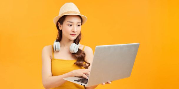 Νεαρή γυναίκα φορούν καπέλο χρησιμοποιώντας φορητό υπολογιστή PC κάνει online περιοδεία κρατήσεων - Φωτογραφία, εικόνα