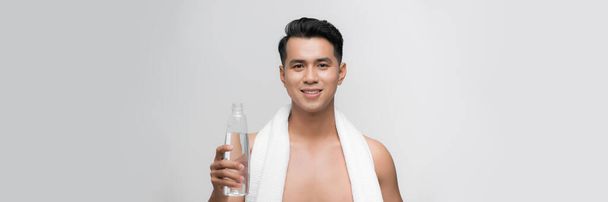 Healthy lifestyle, training and young male with water bottle in hand isolated on gray background studio - Фото, изображение
