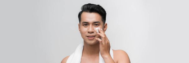 Giovane uomo con crema idratante sul viso - Foto, immagini
