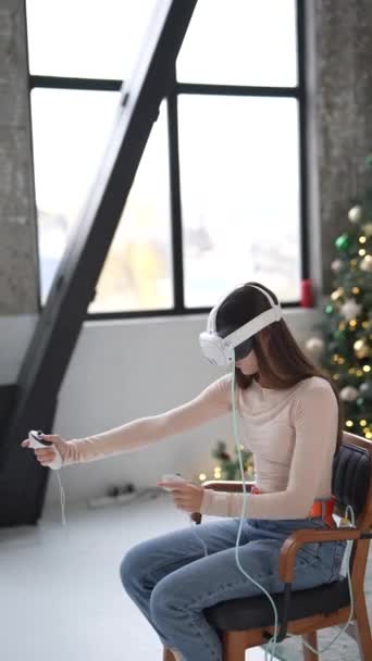 Genç bir kadın Noel süslü bir evde sanal gerçeklik kulaklığıyla oyun oynarken hoş bir anı yakalamak. Yüksek kalite 4k görüntü - Video, Çekim