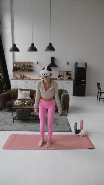 Participando en el ejercicio durante la Navidad, una joven deportista emplea un auricular de realidad virtual. Imágenes de alta calidad 4k - Metraje, vídeo