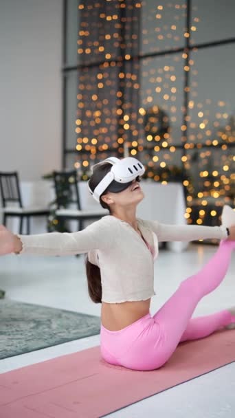 Haciendo ejercicios de piernas durante su entrenamiento en casa, una hermosa mujer joven está en un auricular de realidad virtual. Imágenes de alta calidad 4k - Imágenes, Vídeo