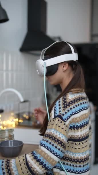 Midden in de kerstvoorbereidingen, een stijlvolle jonge vrouw maakt gebruik van een virtual reality headset tijdens het koken in de keuken. Hoge kwaliteit 4k beeldmateriaal - Video