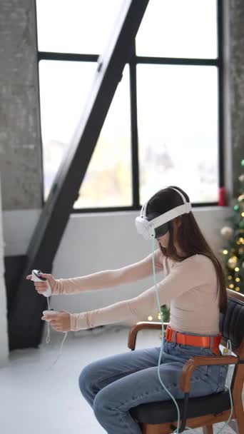 A Christmas tree forms the backdrop as a stylish young woman engages with a virtual reality headset. High quality 4k footage - Footage, Video