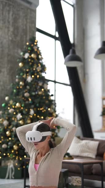 Uma jovem elegante mergulha em ioga em casa durante a temporada de férias, com um fone de ouvido de realidade virtual. Imagens 4k de alta qualidade - Filmagem, Vídeo