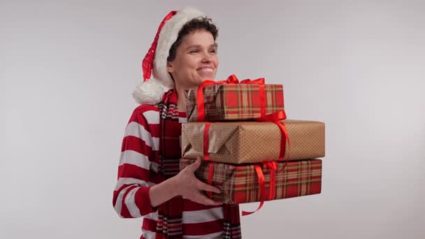 Boldog lány télapó claus kalap kezében egy karácsonyi ajándék fehér háttér. Kiváló minőségű 4k felvételek - Felvétel, videó