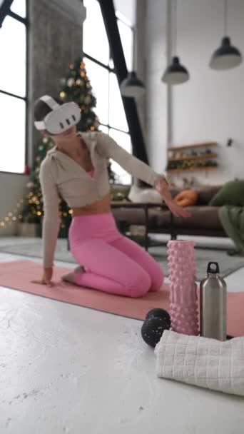 Участвуя в упражнениях разминки тела, она носит гарнитуру виртуальной реальности на розовом коврике для йоги. Высококачественные 4k кадры - Кадры, видео