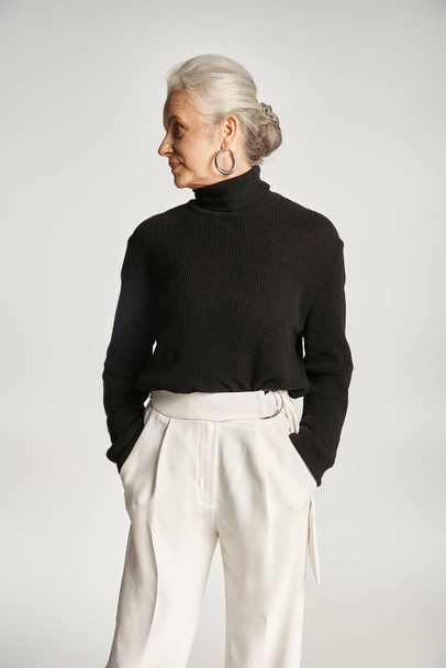 retrato de mujer de negocios de mediana edad en traje elegante posando con las manos en bolsillos en gris - Foto, Imagen