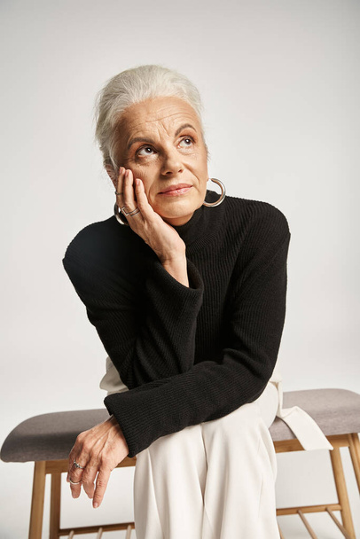 donna d'affari di mezza età in abbigliamento casual intelligente guardando altrove mentre seduto sulla panchina interna - Foto, immagini