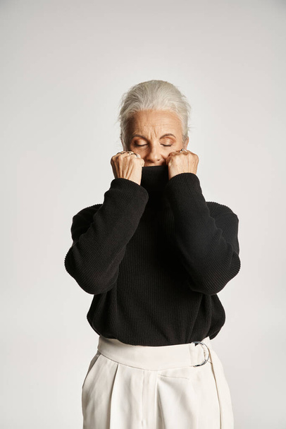 Porträt einer Geschäftsfrau mittleren Alters mit Rollkragen-Pullover vor grauem Hintergrund - Foto, Bild