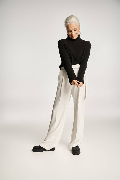 volle Länge der glücklichen Geschäftsfrau mittleren Alters in eleganter schicker Freizeitkleidung posiert auf grau - Foto, Bild
