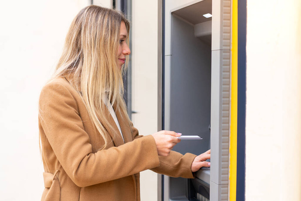 Jovem mulher loira bonita segurando um cartão de crédito ao ar livre - Foto, Imagem