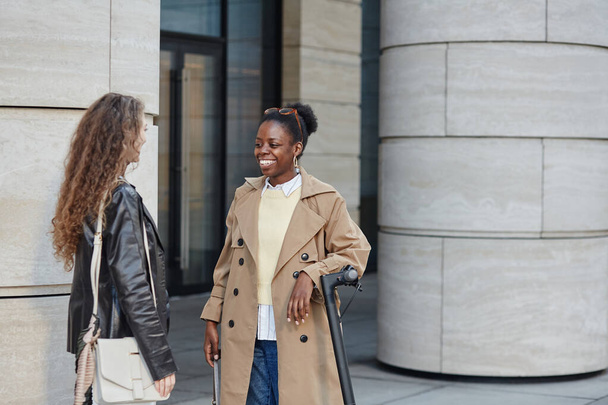 Πορτρέτο της νεαρής μαύρης γυναίκας που μιλάει σε φίλο στο σκηνικό της πόλης και φοράει παλτό, αντίγραφο χώρου - Φωτογραφία, εικόνα