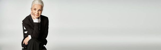 krásná a šedovlasá žena středního věku v elegantním oblečení pózovat na šedém pozadí - Fotografie, Obrázek