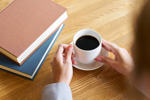 Vrouw die koffie drinkt tijdens het lezen - Foto, afbeelding