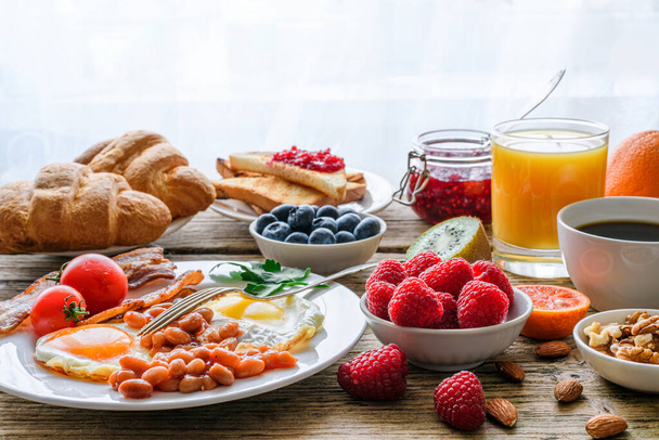 Breakfast buffet. Full english and continental. Large selection of brunch and breakfast food on the table with egg, bacon, toast, orange juice, croissant, coffee, fruits and nuts. - Photo, Image