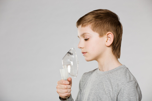 Unhappy boy breathing through inhalator mask on grey background - Zdjęcie, obraz