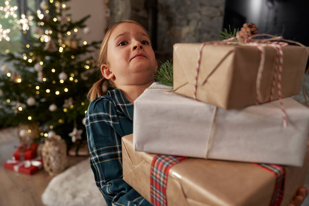 İlköğretim çağındaki kız elinde bir yığın Noel hediyesi bile taşımaz. - Fotoğraf, Görsel