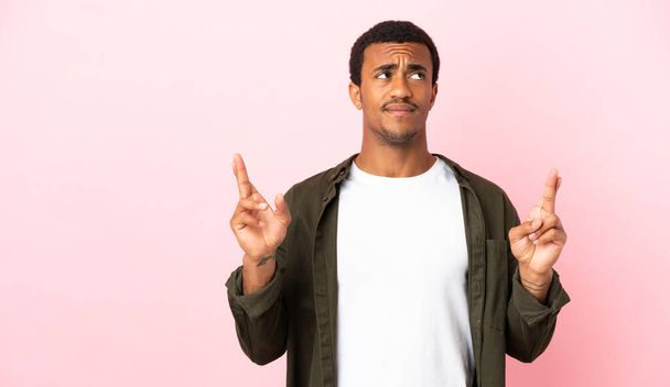 Afroamerikaner auf rosa Hintergrund mit Daumendrücken und besten Wünschen - Foto, Bild