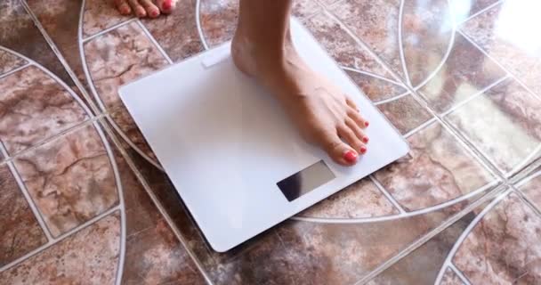 Woman measures weight on scales in morning. Overweight and measurement of body fat concept - Záběry, video