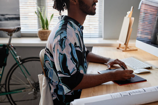 Πλευρική άποψη closeup του νεαρού άνδρα σχεδιαστή χρησιμοποιώντας δισκίο στυλό στο χώρο εργασίας γραφείο στο σπίτι - Φωτογραφία, εικόνα