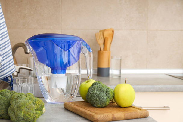 Un filtre à eau se trouve dans la cuisine avec des légumes frais - Photo, image