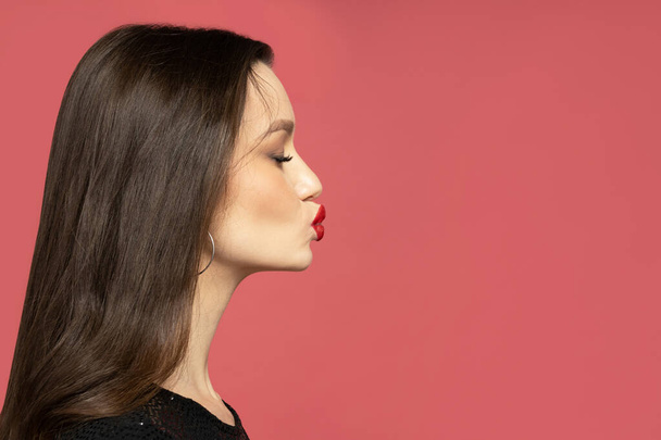A kiss of a pretty brunette on a red background - Photo, Image