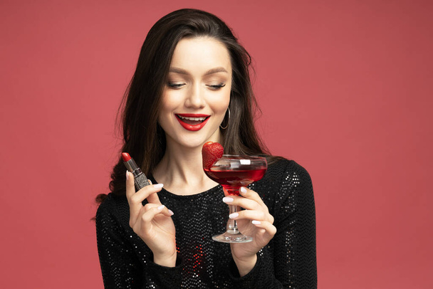 Mooie brunette met lippenstift en een cocktail in haar handen - Foto, afbeelding