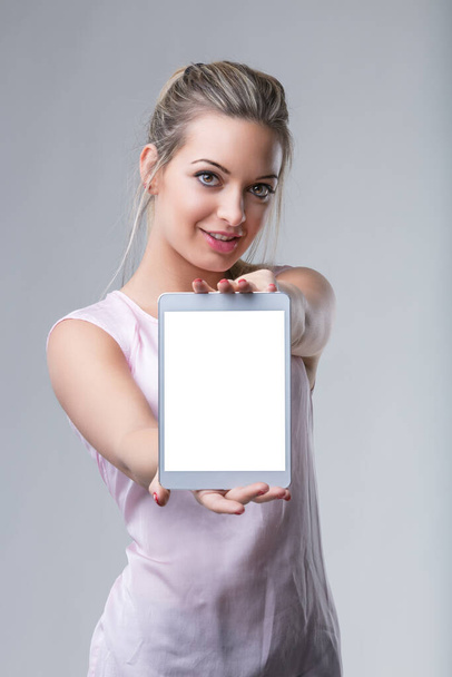 Pewna siebie kobieta prezentuje tablet z pustym ekranem, zapraszając do interakcji - Zdjęcie, obraz