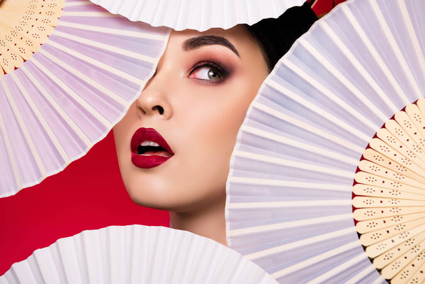Φωτογραφία από κομψό χαριτωμένο ιαπωνική κυρία πρόσωπο visage κόκκινα χείλη αναζητούν κενό χώρο που απομονώνονται σε φόντο κόκκινο χρώμα. - Φωτογραφία, εικόνα