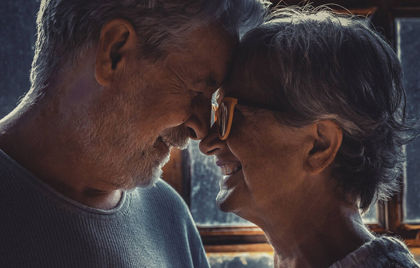 Starší starší pár v lásce a romantické volnočasové aktivity doma tváří v tvář dotýkání se vpředu a usmívání ve vztahu. Zimní dovolená Vánoce uvnitř pro muže a ženu stáří ve štěstí - Fotografie, Obrázek