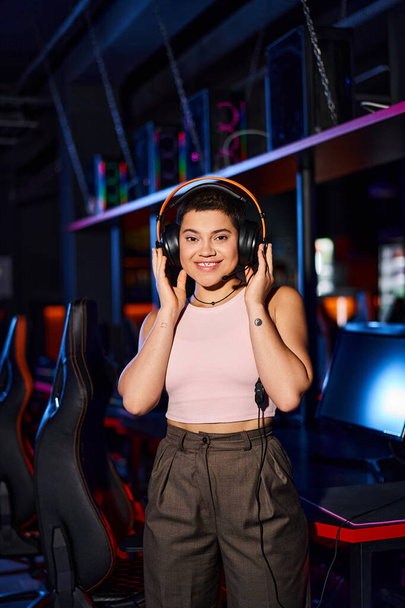 A stylish young woman in indoor setting wearing headphones, immersing herself in music - Photo, Image