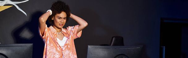 femme afro-américaine frustrée avec les cheveux bouclés regardant l'ordinateur et stressant, bannière - Photo, image