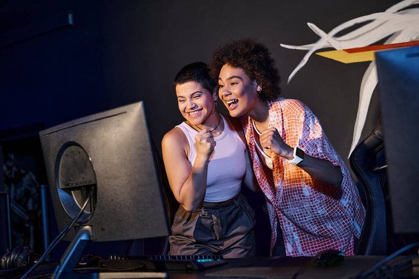 kaksi rotujenvälinen ja onnellinen naiset juhlivat voittoa voitettuaan pelihuoneessa, cybersport - Valokuva, kuva