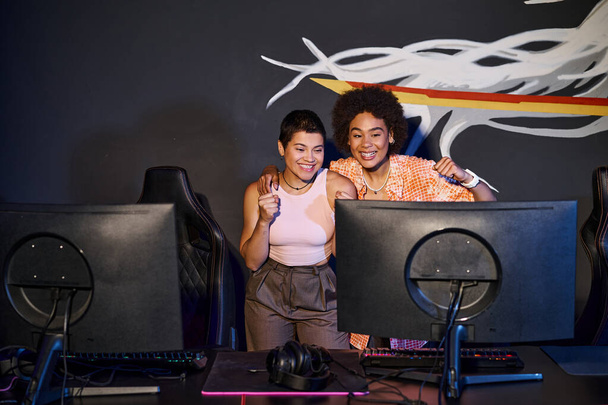 мультикультурные и счастливые друзья смотрят на монитор компьютера и празднуют победу, киберспорт - Фото, изображение