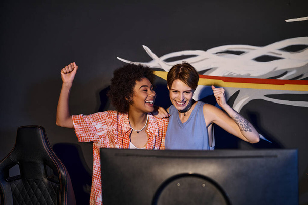 мультикультурні щасливі друзі, які дивляться на монітор комп'ютера і святкують перемогу, кіберспорт - Фото, зображення