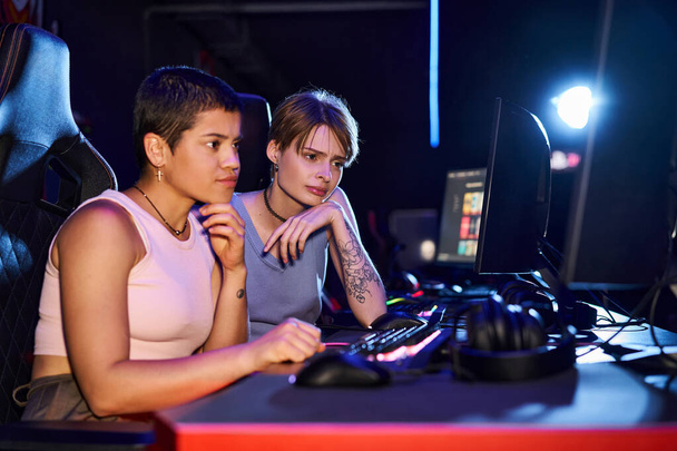 Дві жінки з татуюваннями зосереджені на кіберспортивній грі в кімнаті комп'ютерного клубу, жіночі геймери - Фото, зображення