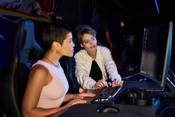 two women focused on a cybersport gaming session, female players thinking on game strategy - Photo, Image