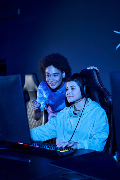 sonrientes mujeres interracial se centró en una sesión de juego de ciberdeporte, amigas mirando monitor - Foto, imagen