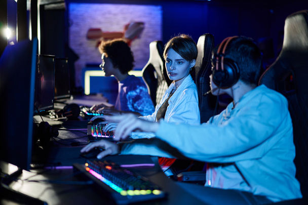 focus on young woman with short hair giving advice on game strategy to female player near monitor - Photo, Image