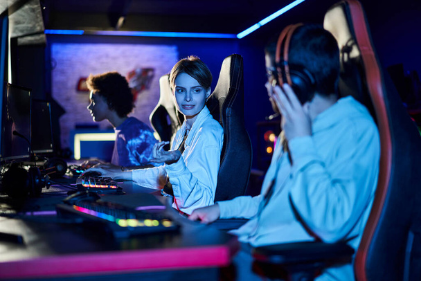 focus on smiling woman with short hair giving advice on game strategy to female player near monitor - Photo, Image