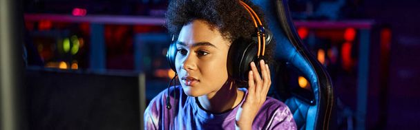 jugador afroamericano en auriculares mirando monitor jugando juego de ordenador, banner ciberdeporte - Foto, Imagen