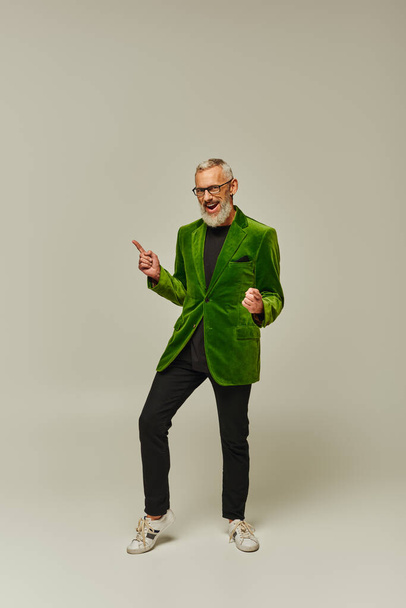 joyful handsome mature male model in stylish outfit with beard and glasses smiling at camera - Фото, изображение