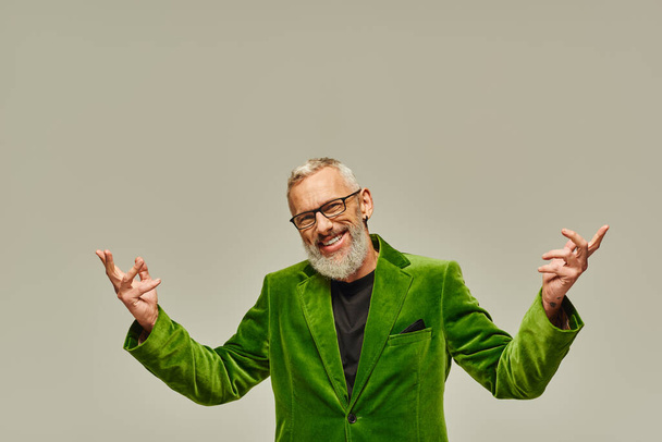 весёлый красивый зрелый мужчина-модель в ярко-зелёном блейзере позирует и счастливо улыбается в камеру - Фото, изображение