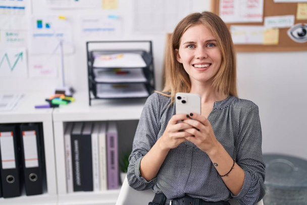 Mujer joven rubia trabajadora de negocios usando smartphone trabajando en la oficina - Foto, Imagen