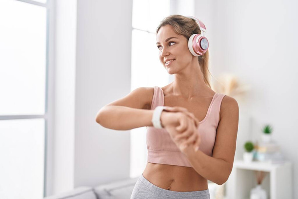 Junge blonde Frau hört zu Hause Musik mit Stoppuhr - Foto, Bild